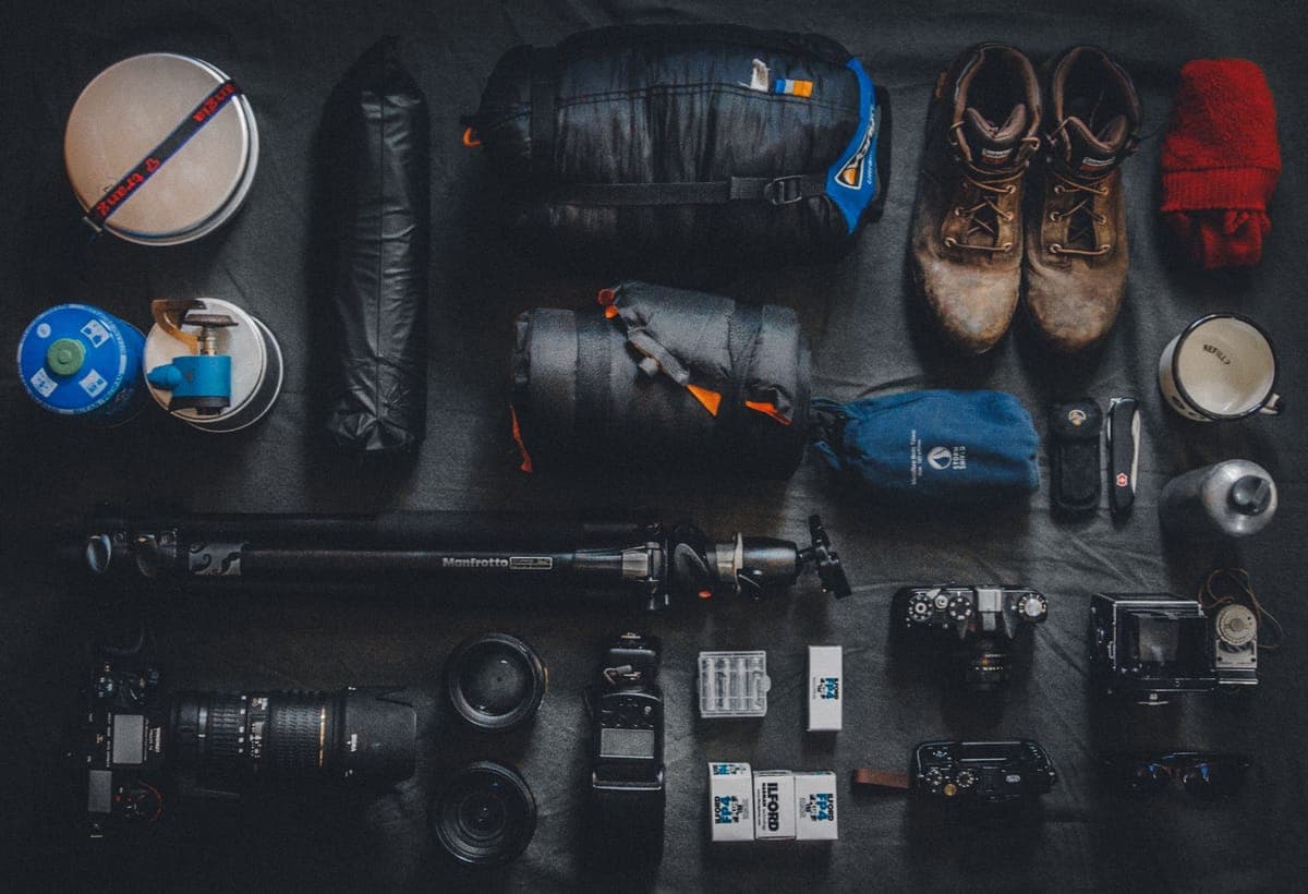 Outdoor gear laid out flat including a backpack and accessories