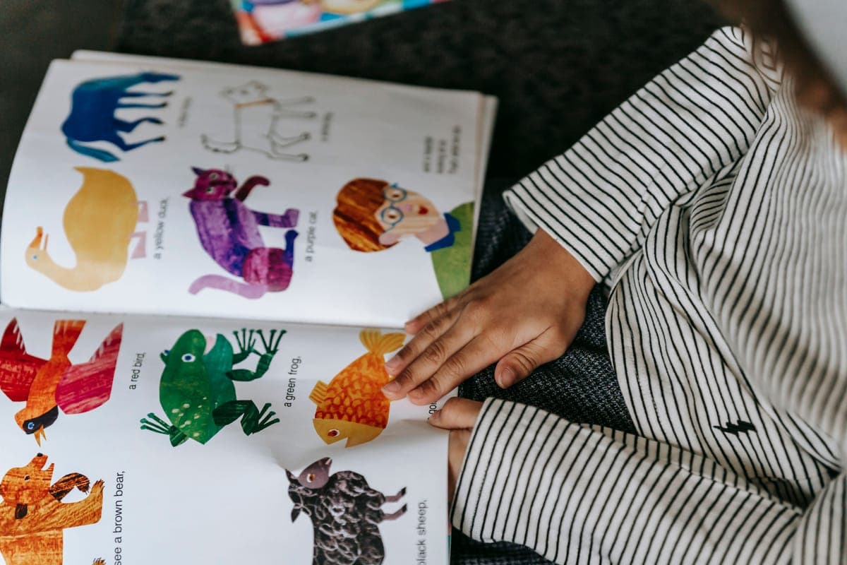 A child reading an illustrated book about animals