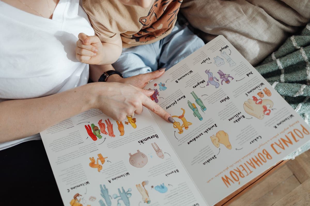 An adult and a small child reading a colorful picture book together