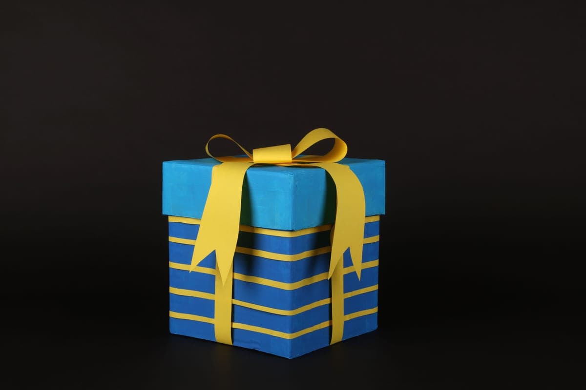 A blue gift box tied with a yellow ribbon on a dark background