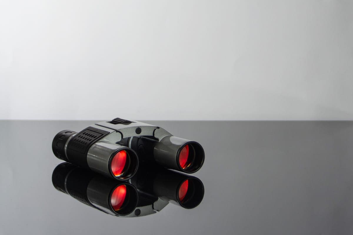 Modern binoculars with coated lenses on a dark reflective surface