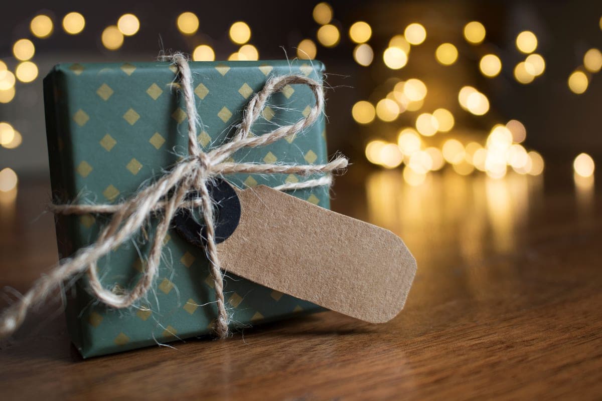 A small wrapped gift with twine beside warm festive lights