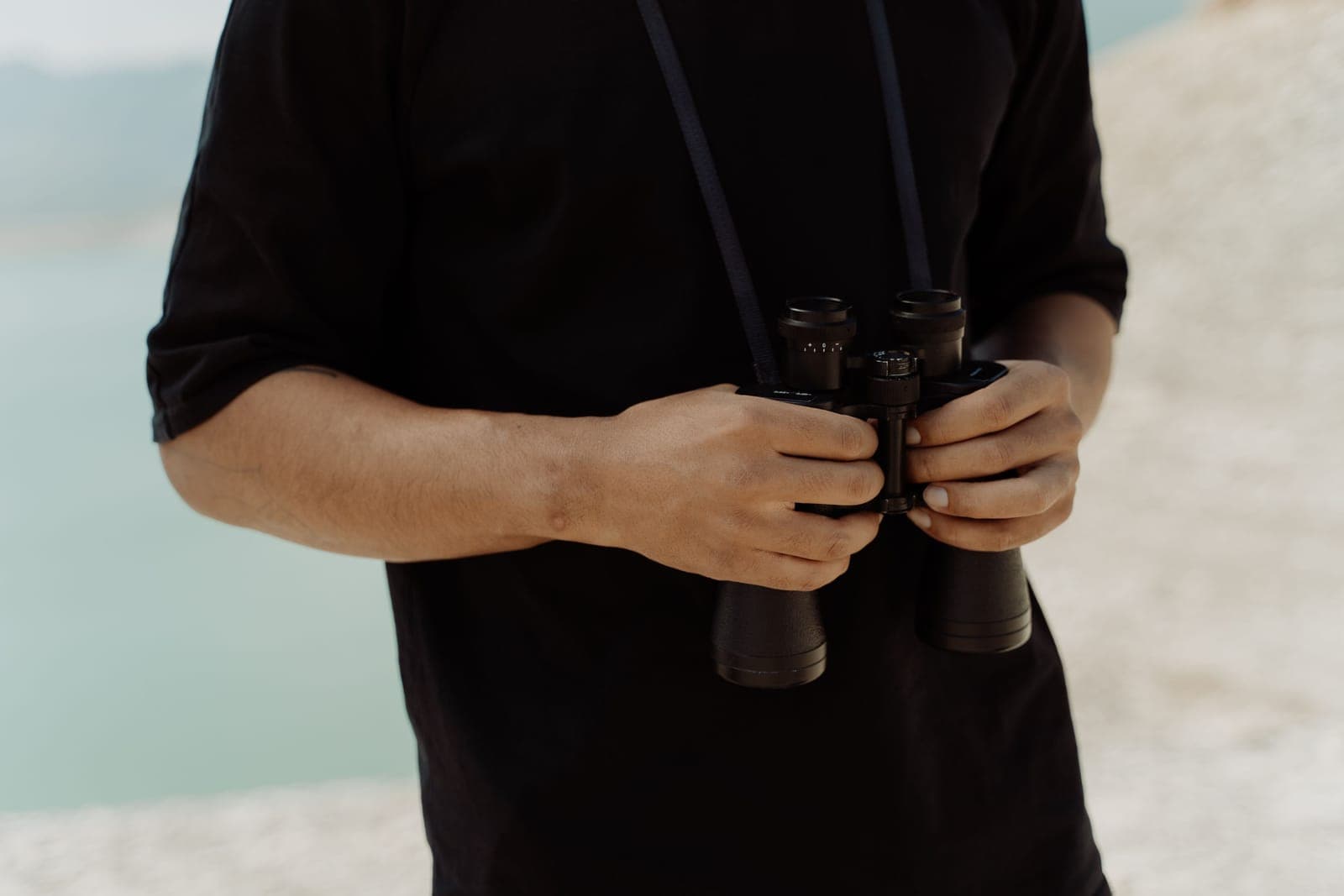 A person holding binoculars while standing outdoors