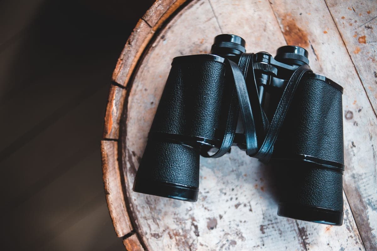 A close-up of binoculars resting on a rustic wooden table