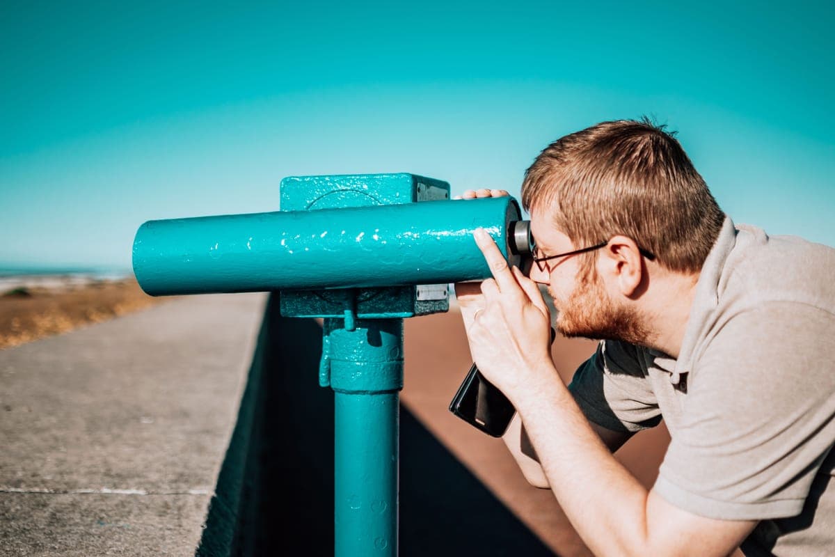 A person using coin-operated viewing binoculars on a sunny day