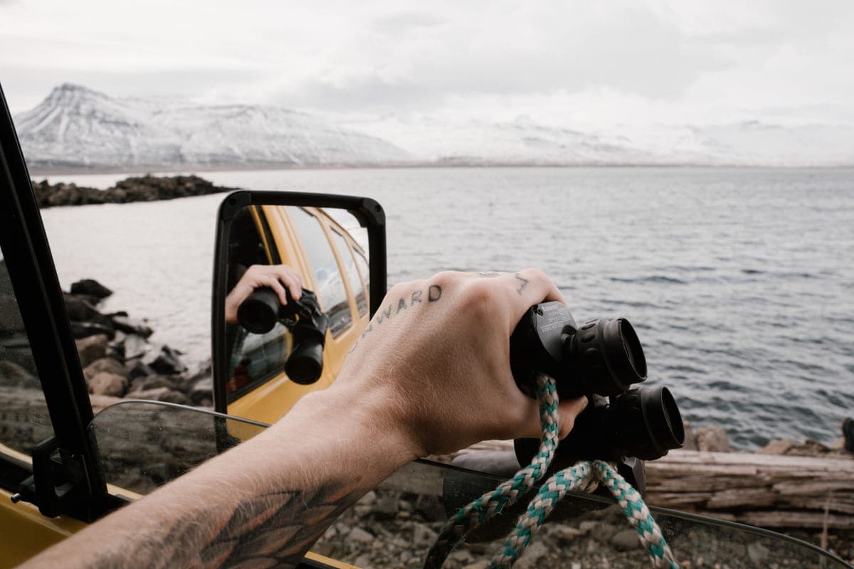 A pair of binoculars held up against a mountain landscape